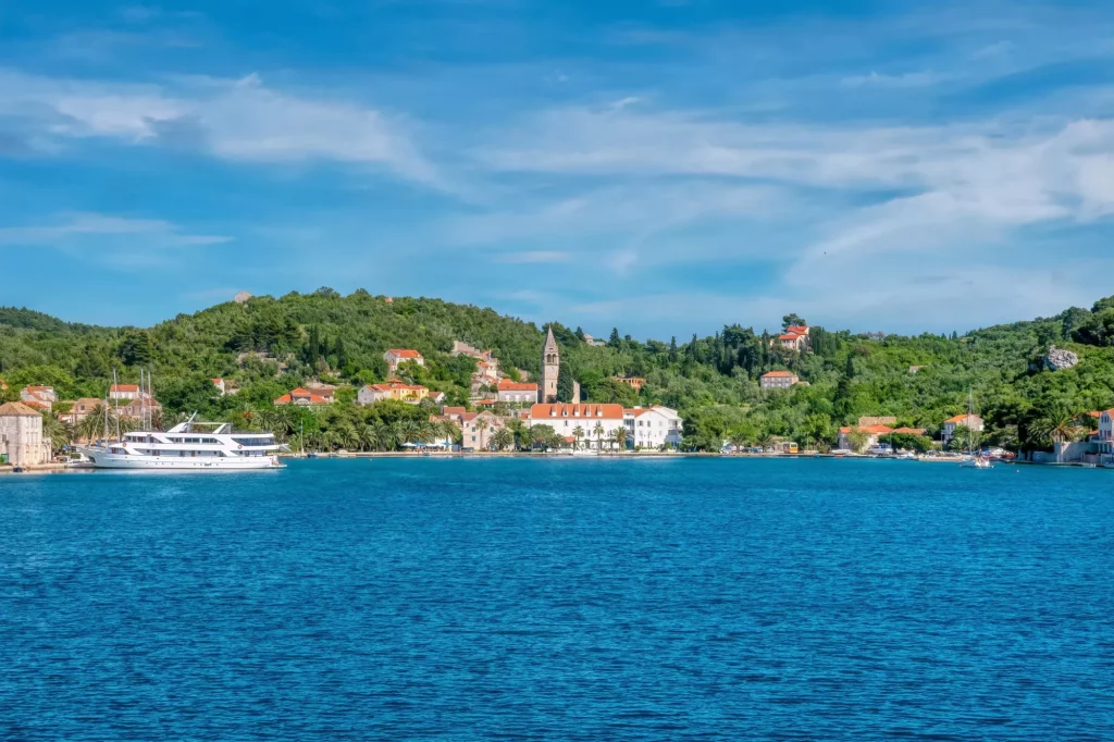 Vi nærmer os med båd og har udsigt til den maleriske landsby Sipanska Luka på Sipan, en af Elaphiti-øerne på den dalmatiske kyst i Kroatien.