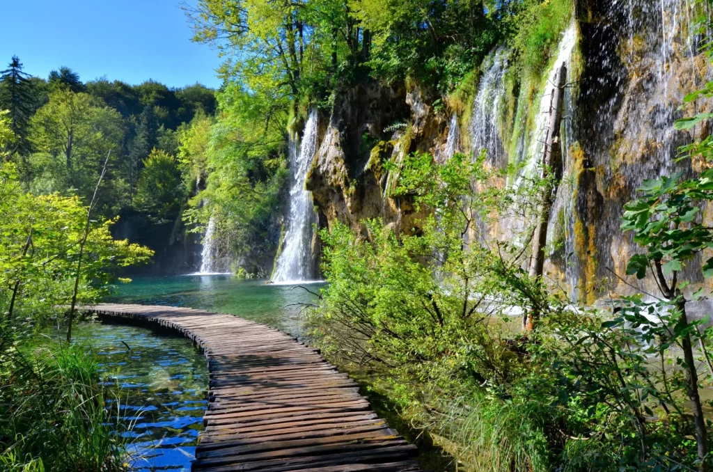 Strandpromenad genom vattenfallen i nationalparken Plitvicesjöarna, Kroatien